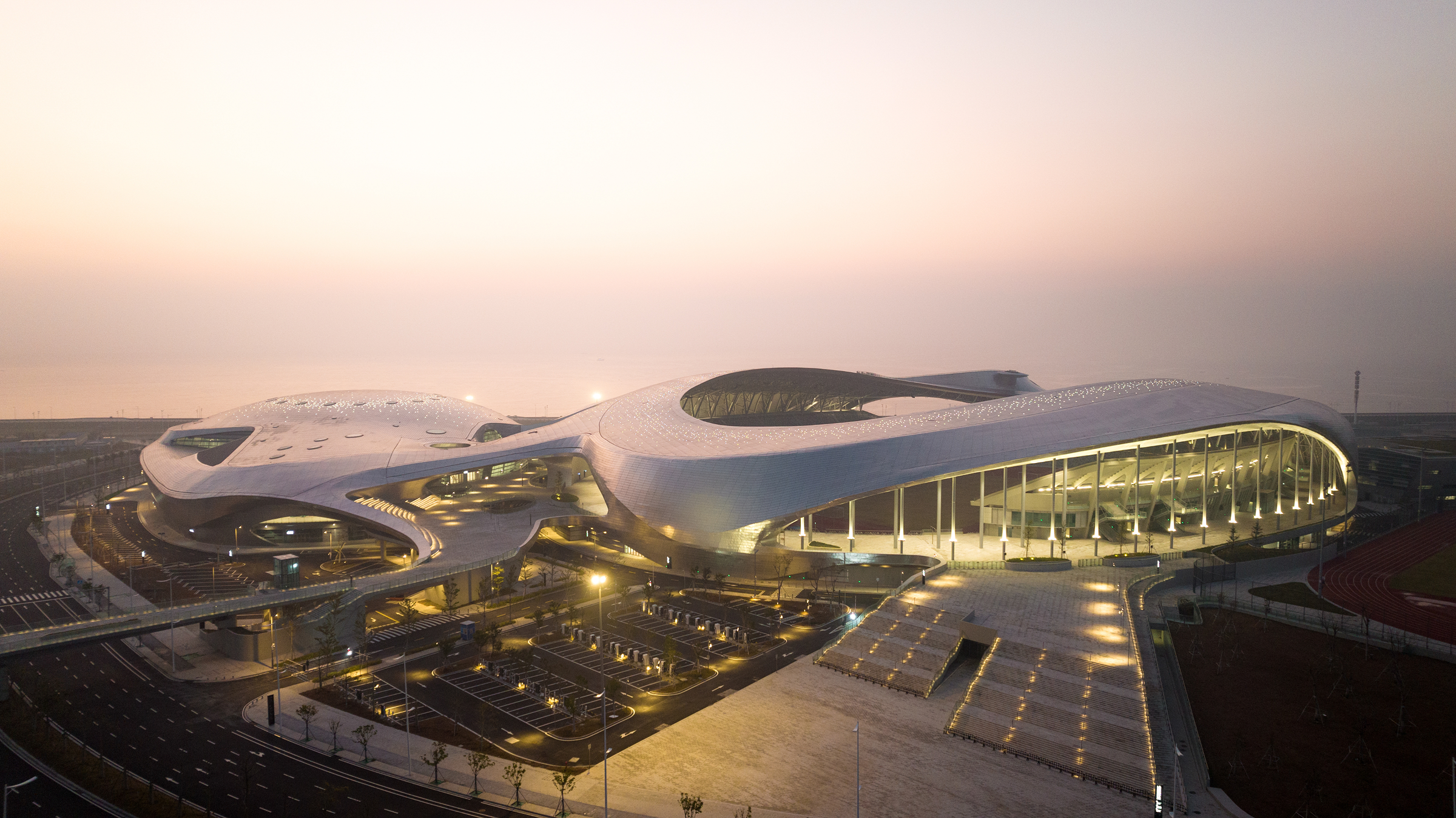 Night aerial view of the venue complex lit against the Shantou coastline.