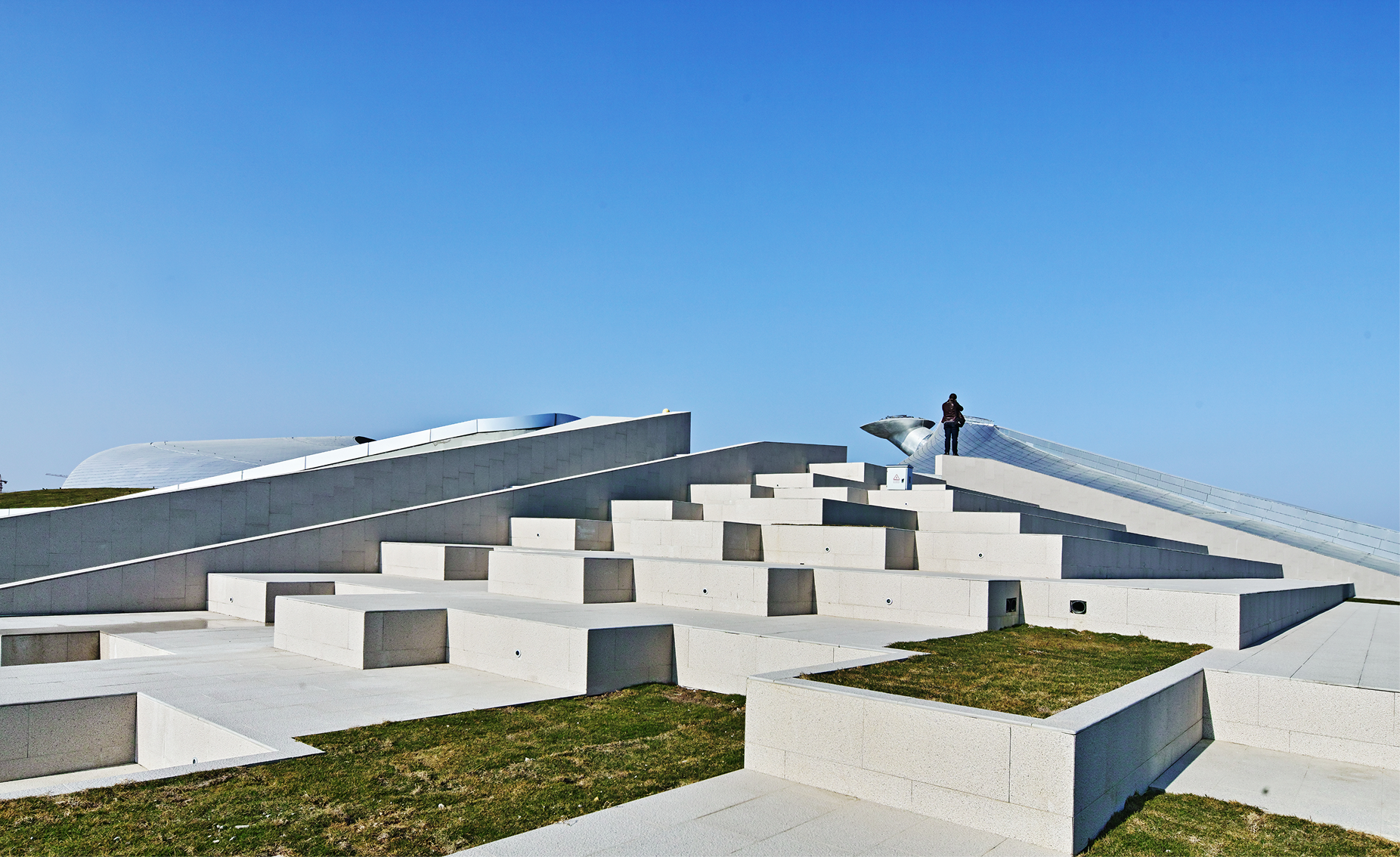 Wide view of the public platform and landscaped open space surrounding the venue.