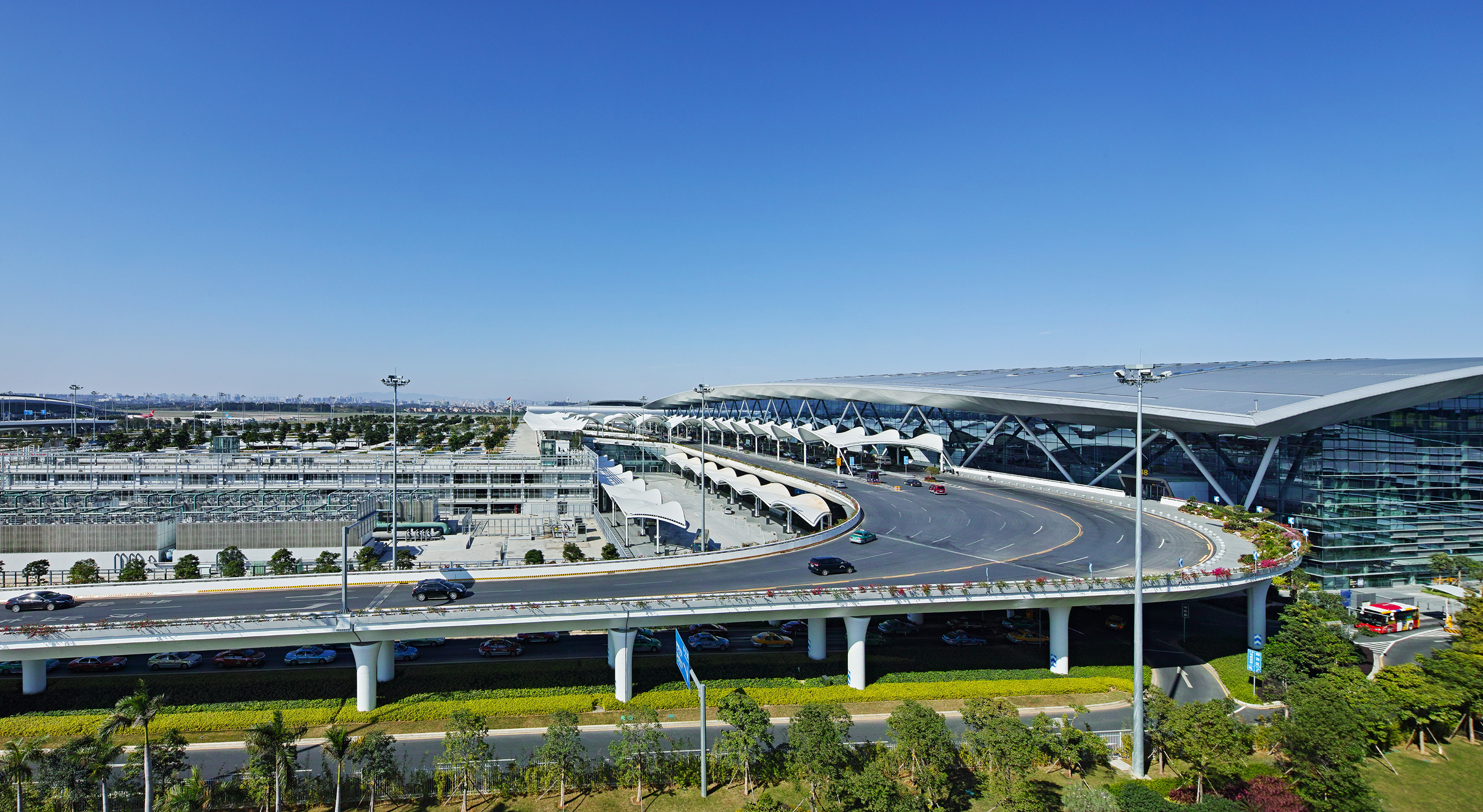 Daytime landside aerial view of the terminal and surrounding access infrastructure.